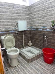 a bathroom with a toilet and a bucket at Eagles Nest Muzaffarabad in Muzaffarabad