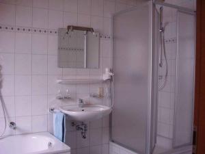 ein weißes Bad mit einem Waschbecken und einer Dusche in der Unterkunft Gasthof Zum Schützen in Oberprechtal