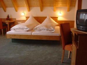 a bedroom with a bed with pillows and a tv at Gasthof Zum Schützen in Oberprechtal