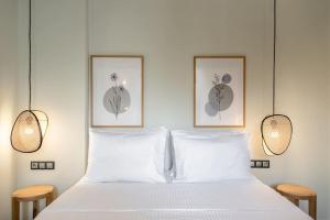 a white bed with three pictures on the wall at Coco-Mat Efterpi House by Plakias Suites in Plakias