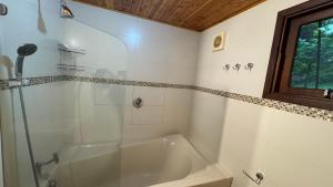 bagno bianco con vasca e finestra di Casa Centro MONTE VERDE,MG 12 PESSOAS a Monte Verde Altre 25 foto