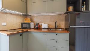 cocina con armarios blancos, fregadero y nevera en Pátio Vilareto - Villa Clara, en São Domingos de Rana