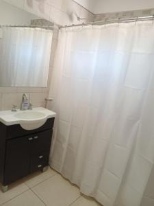 a bathroom with a sink and a white shower curtain at Dpto Posadas in Junín