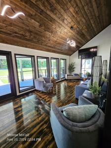 a living room with couches and chairs and windows at Life's Good Retreat Main House in Brevard