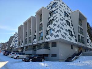 a building with cars parked in a parking lot at A-Apartman in Bjelašnica