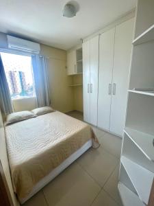 a bedroom with a bed and white cabinets and a window at Apartamento Conforto/Praticidade in Manaus