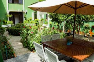 ein Holztisch mit einem Sonnenschirm im Garten in der Unterkunft Hotel Jarumã in Abaetetuba
