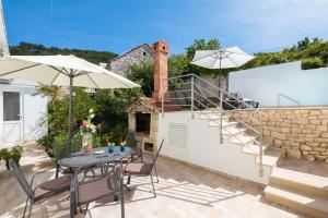 a patio with a table and chairs and a brick wall at House Andre in Nerežišća