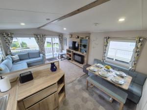 a caravan living room with a table and a couch at Whitstable Neptune in Kent