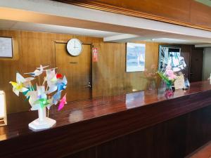 a reception desk with a clock and flowers on it at Hotel Kaishunro - Vacation STAY 54369v in Hamamatsu