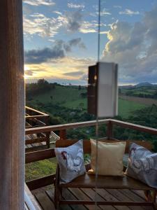 a wooden bench with pillows on a balcony with a view at Chacrinha pousada e restaurante in Caldas