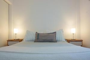 a white bed with two lamps on two tables at Departamento 2 Premium con Cochera y Piscina in Bahía Blanca +29 photos