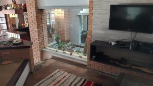 sala de estar con TV de pantalla plana en una pared de ladrillo en Jardim Aruan, Caraguatatuba ,sp, en Caraguatatuba