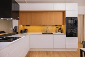 a white kitchen with wooden cabinets and appliances at Northern Lights River in Rovaniemi