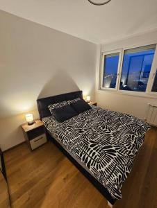 a bedroom with a black and white bed and two windows at Skyline Cozy Suites in Novi Sad