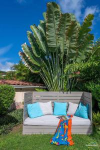 a white couch with pillows on the grass with a palm tree at Villa Bleue, piscine, vue mer in Le Diamant