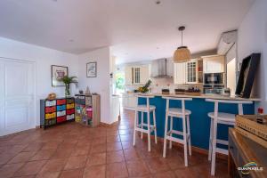 a kitchen with a blue counter and stools in it at Villa Bleue, piscine, vue mer in Le Diamant