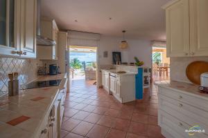 a large kitchen with white cabinets and a tile floor at Villa Bleue, piscine, vue mer in Le Diamant