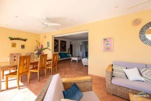 a living room and dining room with a couch and a table at Villa Bleue, piscine, vue mer in Le Diamant
