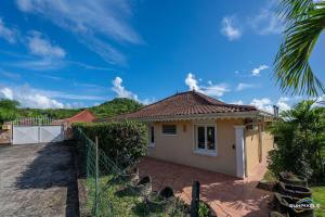 a small house with a fence in front of it at Villa Bleue, piscine, vue mer in Le Diamant