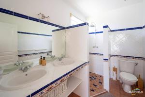 a white bathroom with two sinks and a toilet at Villa Bleue, piscine, vue mer in Le Diamant