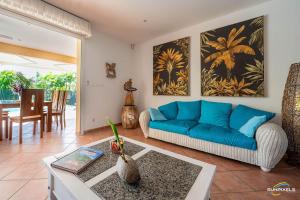 a living room with a blue couch and a table at Villa Bleue, piscine, vue mer in Le Diamant