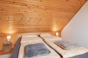 two beds in a room with a wooden ceiling at Holiday House Podhamer Boris with private Wellness in Ljutomer