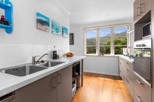 a kitchen with a sink and a large window at Belmont Beach House - Whangarei Heads Escape in Whangarei