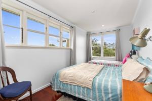 a bedroom with a bed and a desk and windows at Belmont Beach House - Whangarei Heads Escape in Whangarei