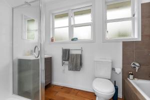 a bathroom with a toilet and a shower and windows at Belmont Beach House - Whangarei Heads Escape in Whangarei +13 photos