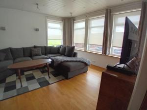 a living room with a couch and a tv at Hóll Guesthouse in Akranes