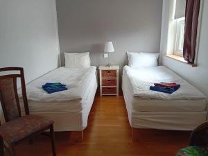 two beds in a room with a chair and a table at Hóll Guesthouse in Akranes