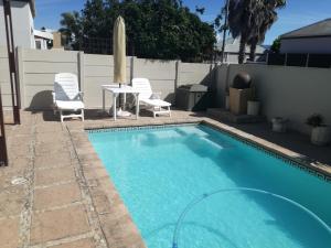 a swimming pool with chairs and a table next to a fence at Captain's Sea Cabin in Cape Town