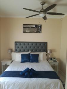 a bedroom with a bed with blue pillows and a ceiling fan at Captain's Sea Cabin in Cape Town +12 photos