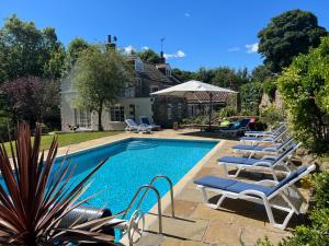 a swimming pool with lounge chairs next to a house at The Exclusive 6 bedroom Farm House, Markington incl heated pool and The Richmond Hill one bedroom Cottage in Ingerthorpe