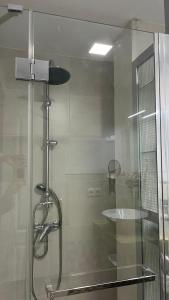una ducha con una puerta de cristal junto a un lavabo en Edsan, en Madrid
