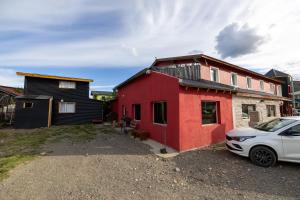 a red and black house with a car parked next to it at Mistico Hostel 23 in El Chalten