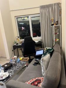 a living room with a couch and a desk with a laptop at 1BHK Furnished Apartment in Dubai