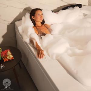 une femme allongée dans une baignoire remplie de mousse dans l'établissement Livia Residence, à Antalya