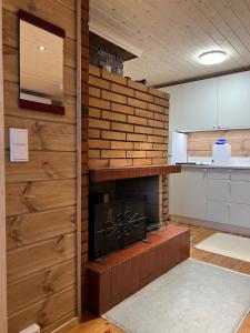 a kitchen with a brick wall with a fireplace at Traditional lakeside cottage in Rovaniemi