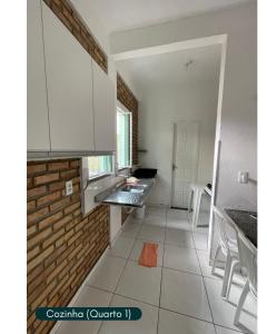 a kitchen with white cabinets and a brick wall at Condomínio Chalés Santo Antônio - Flecheiras in Trairi