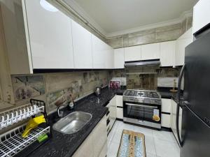 a kitchen with white cabinets and a sink and a refrigerator at Spacious 3BR Apt, 2 Baths, Gated Community - 803 in Sheikh Zayed