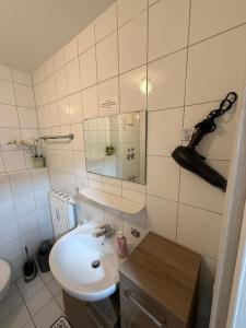 a white bathroom with a sink and a mirror at Ferienwohnung Hess in Rust
