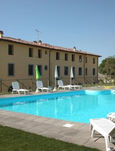 un hotel con piscina con sedie e un edificio di Residence Giuly Rosselmini a Pieve di Santa Luce