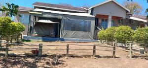 a house with a tent in front of it at Aacron Hills Guesthouse in Kasane