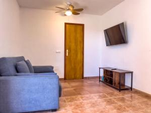 Una sala de estar con un sofá azul y un televisor. en Can Pep Yern 2, en Playa de Migjorn