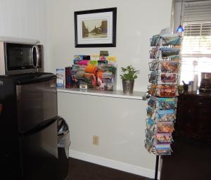 a room with a refrigerator and a shelf with books at Haven Hotel - Fort Lauderdale Airport & Cruise Port in Fort Lauderdale