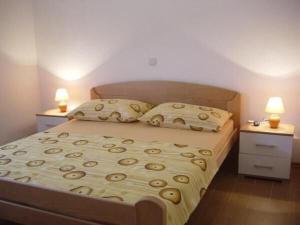 a bedroom with a bed with two night stands and two lamps at Apartments Vladimir in Malinska