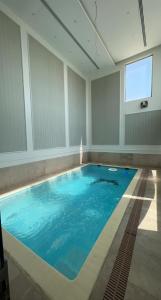 a large swimming pool with blue water in a room at شاليه كادي cady resort in Al Khobar