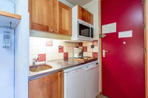 une petite cuisine avec un évier et une porte rouge dans l'établissement Résidence Cristallin G - CRISTALLIN 1 MAE-2621, à Valmorel 4 autres photos